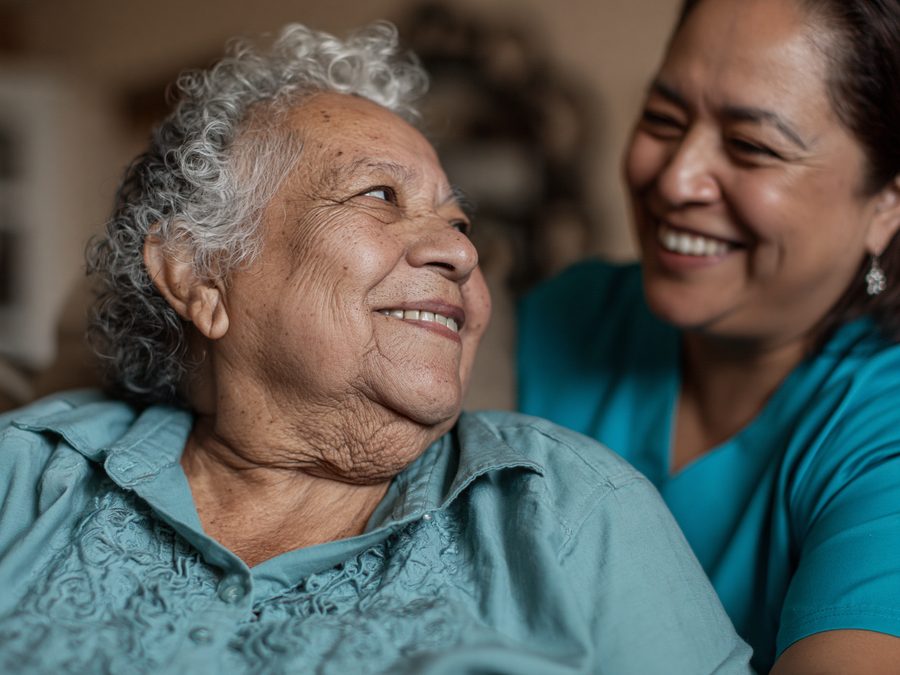 Latina nurse laughing with elderly grandmother — joy and connection