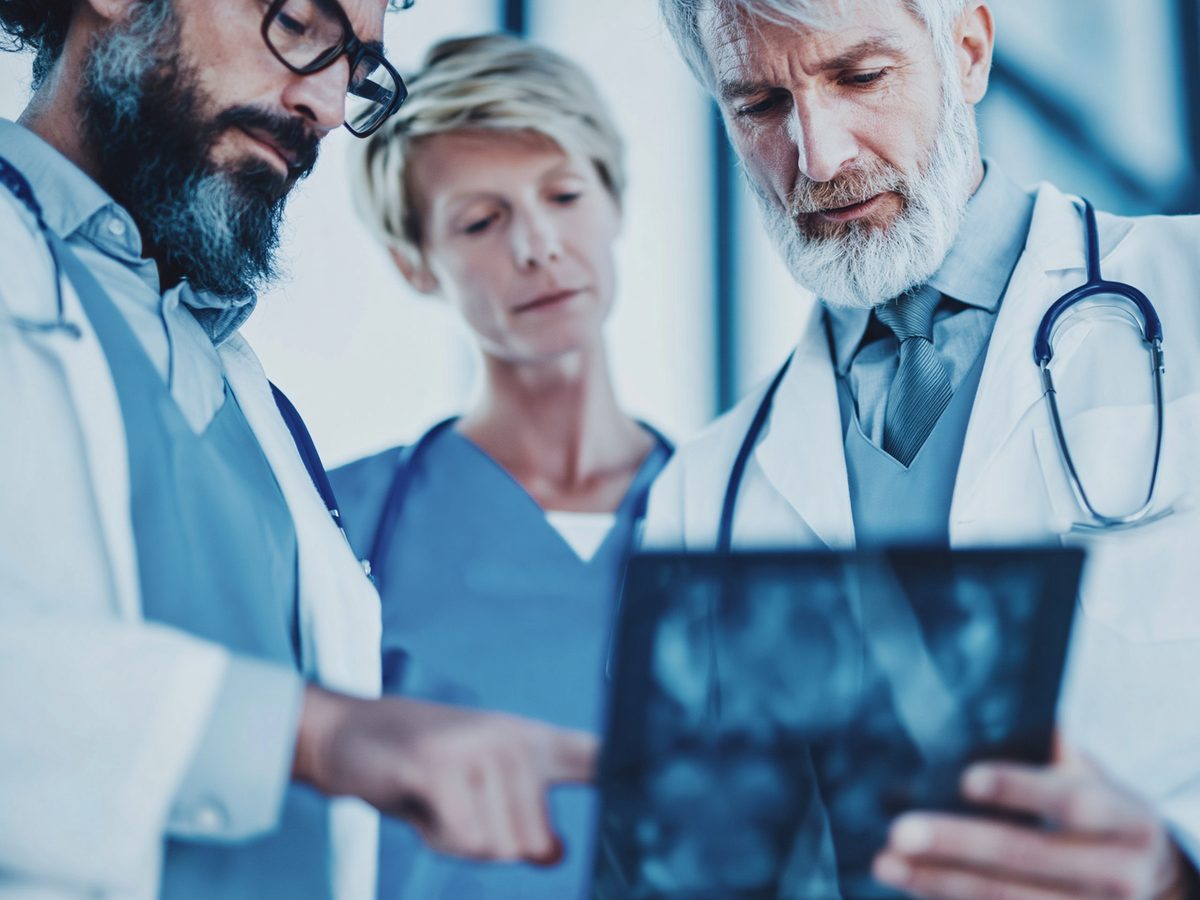 Three clinicians collaborating on a patient case, reviewing imaging together
